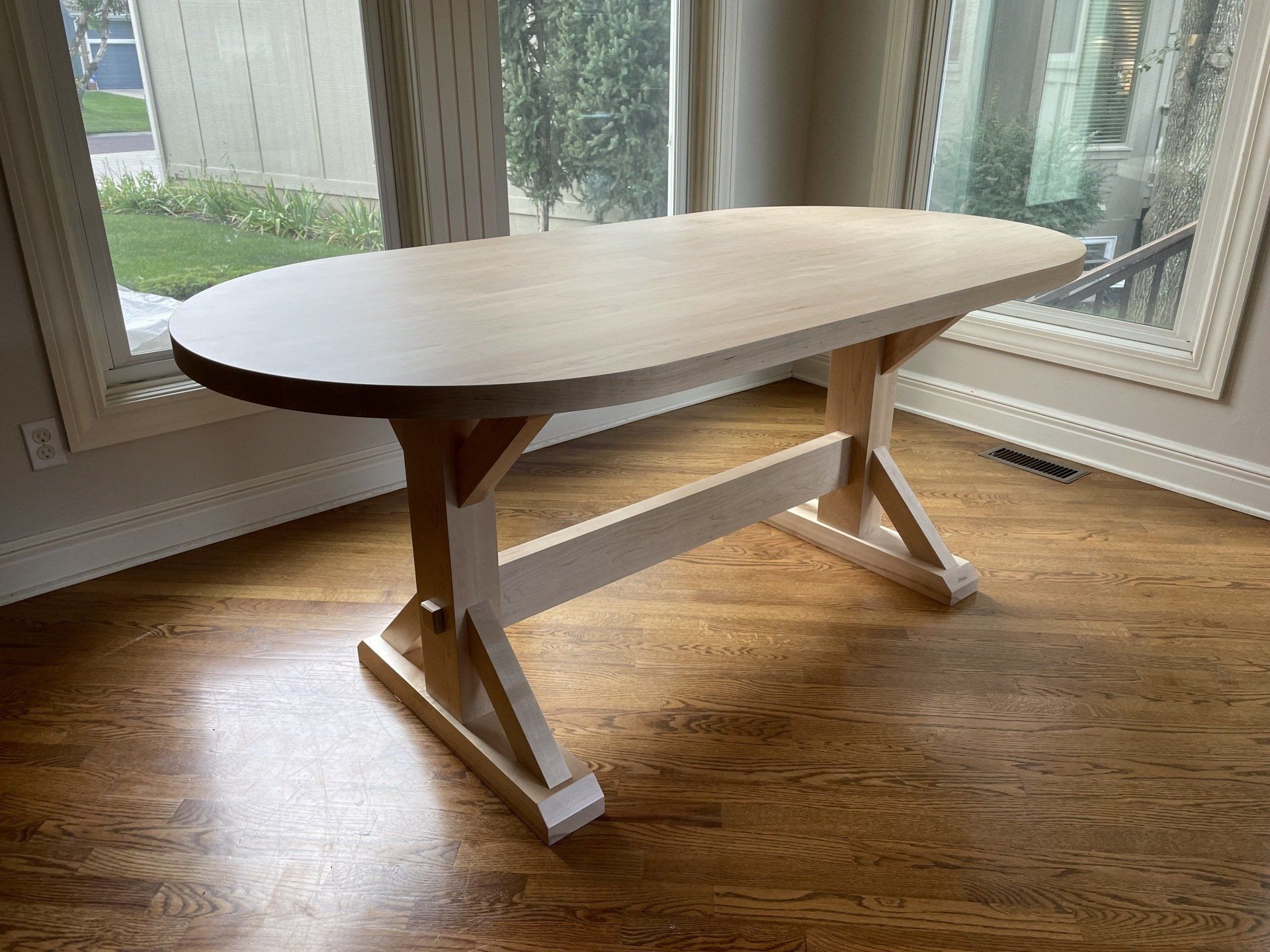 A wooden table is sitting in a living room next to a window.