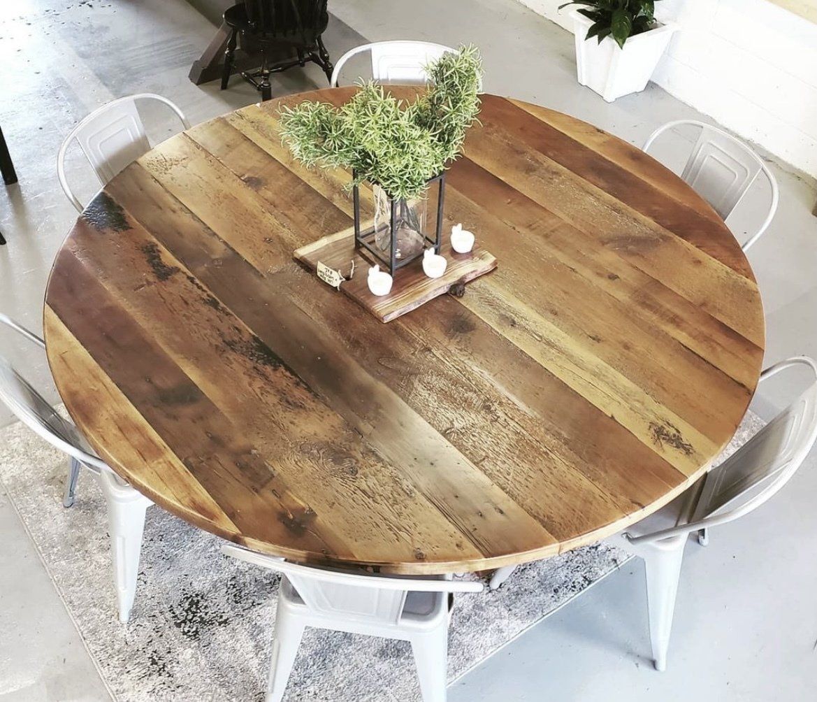 A round wooden table with a vase of flowers on it