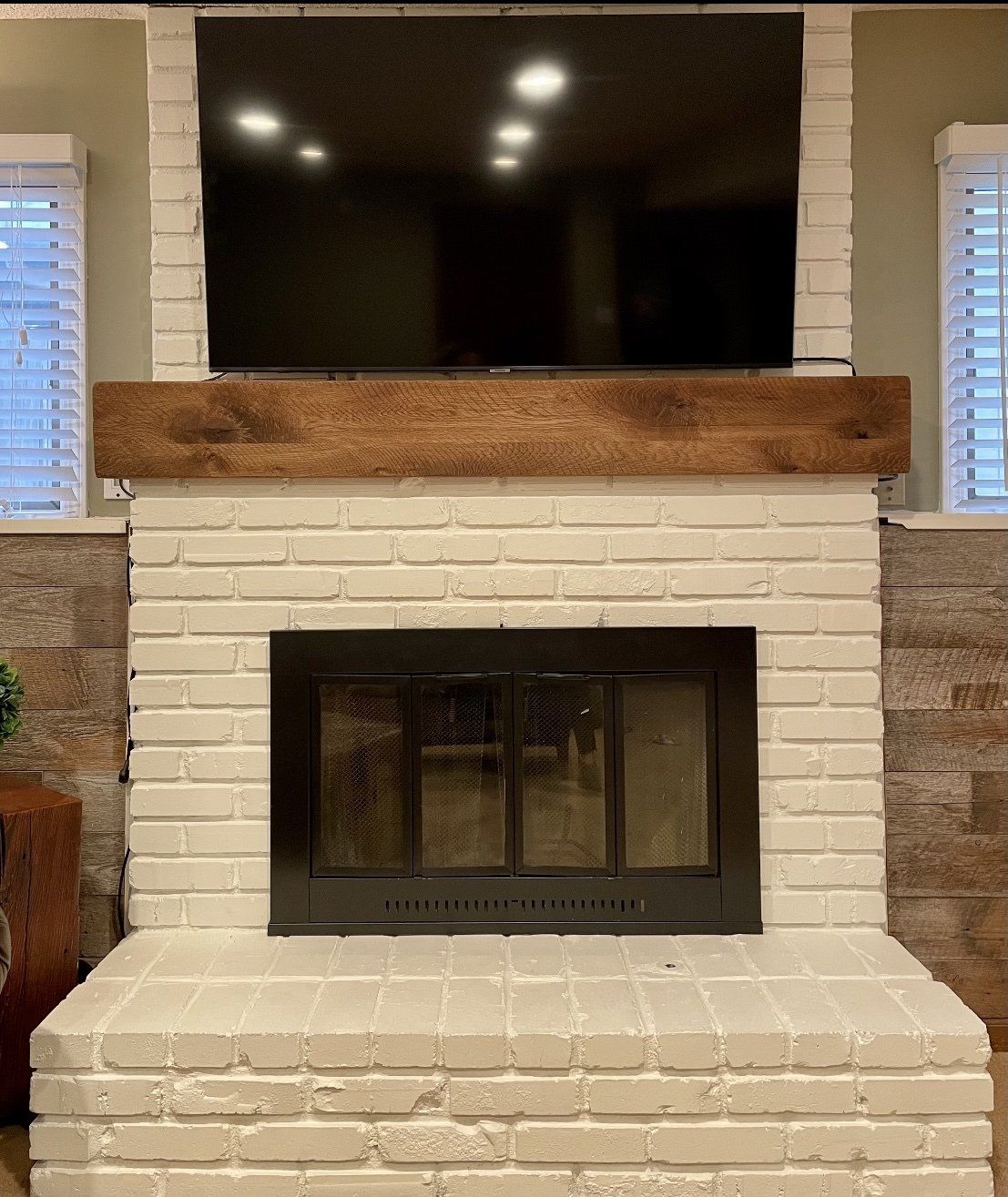 A white brick fireplace with a flat screen tv above it.