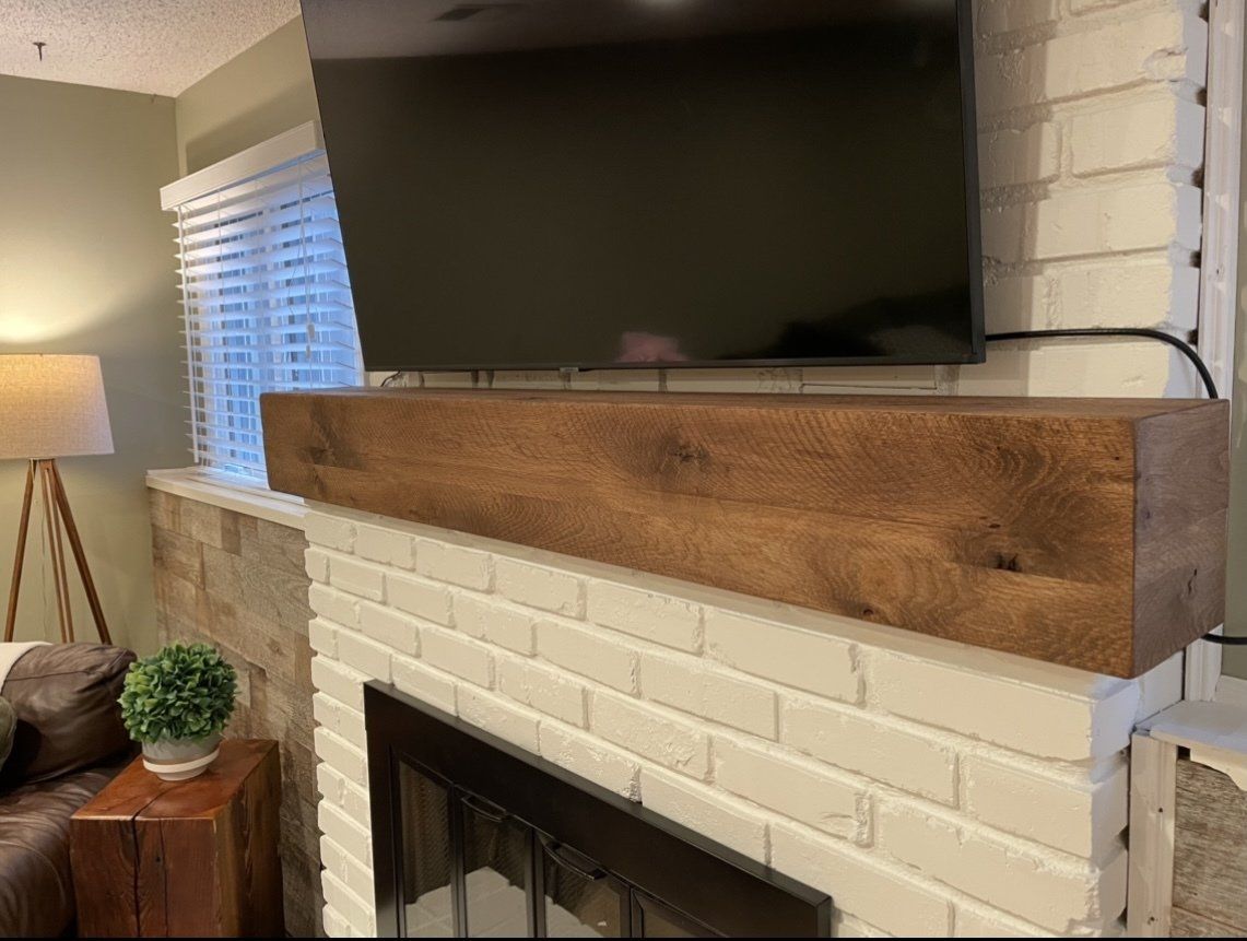 A fireplace with a wooden mantle and a flat screen tv above it.