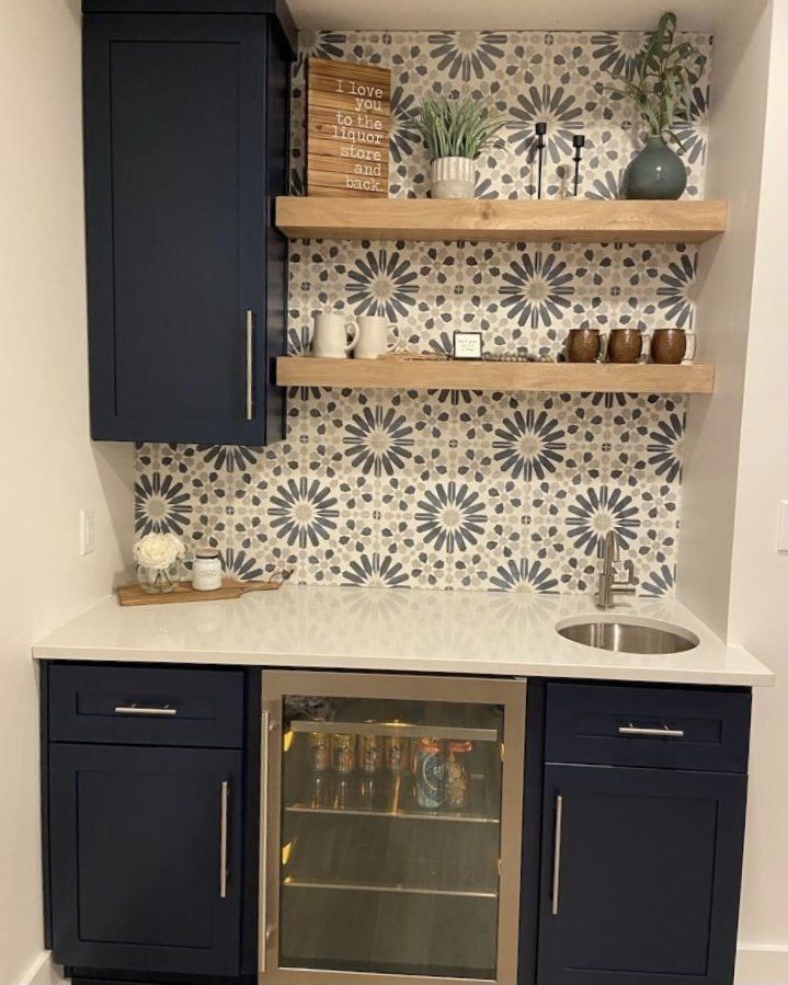 A kitchen with blue cabinets , a sink , and a refrigerator.