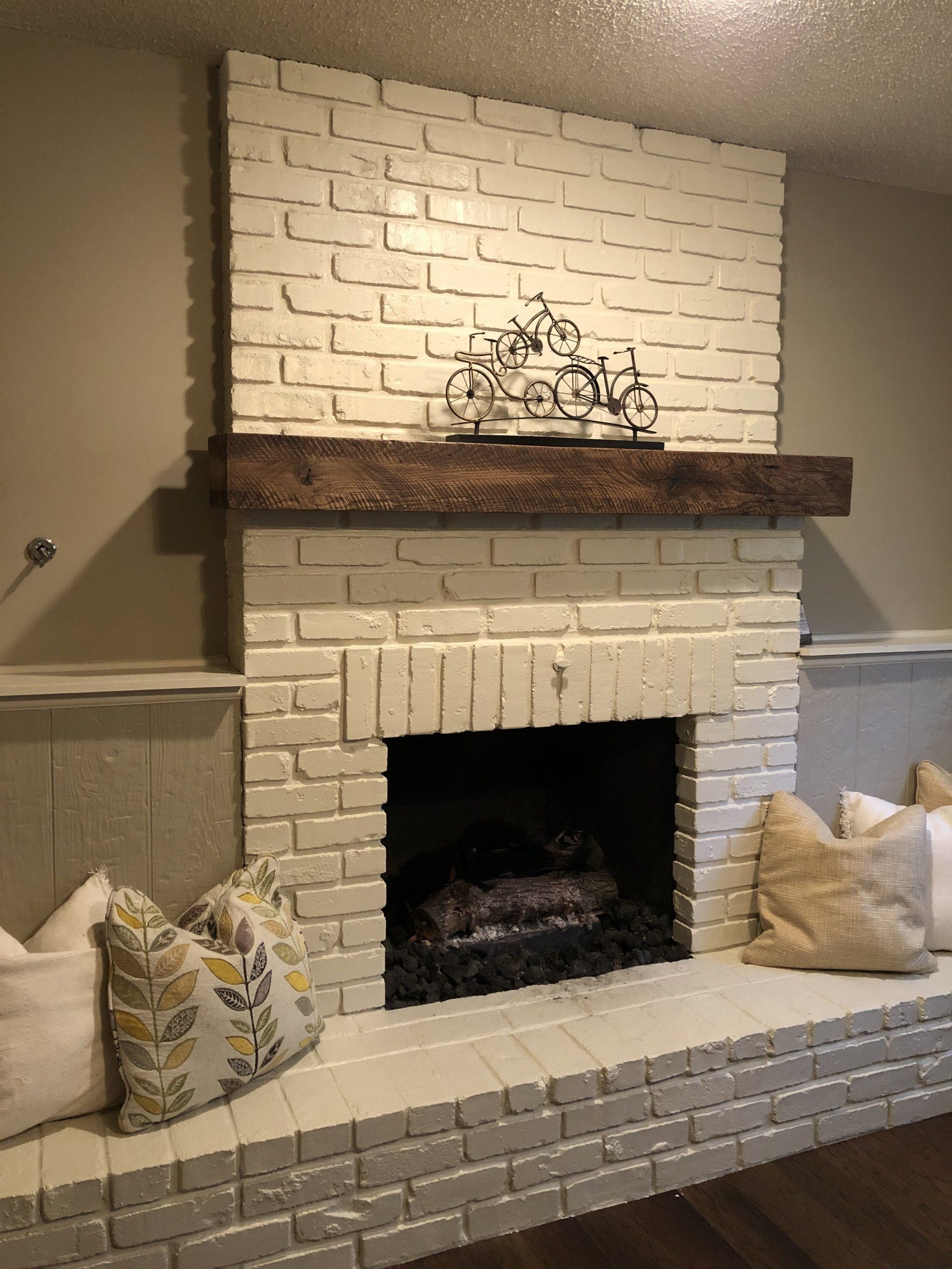 A white brick fireplace with a wooden mantle in a living room