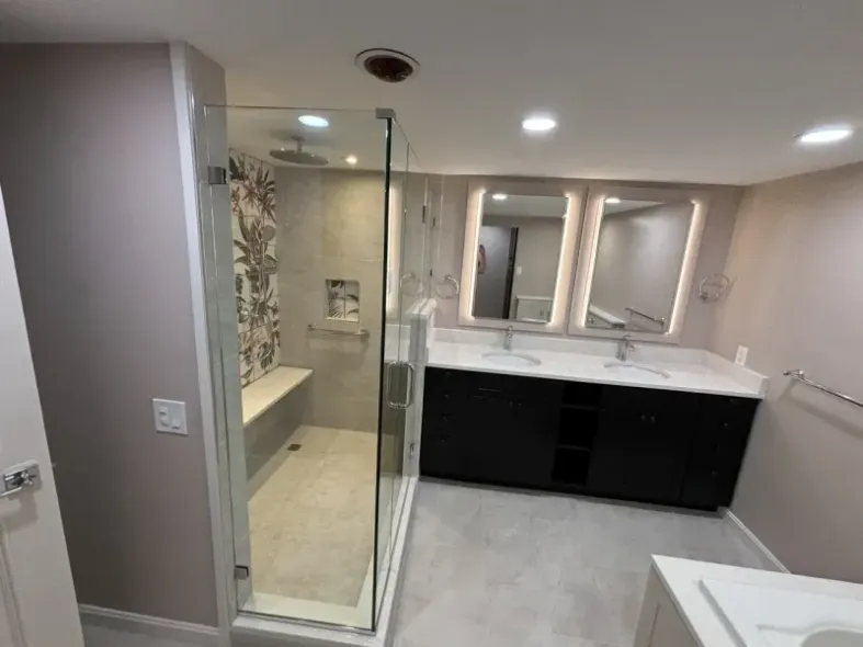 Modern bathroom with glass shower, double vanity, and neutral color scheme.