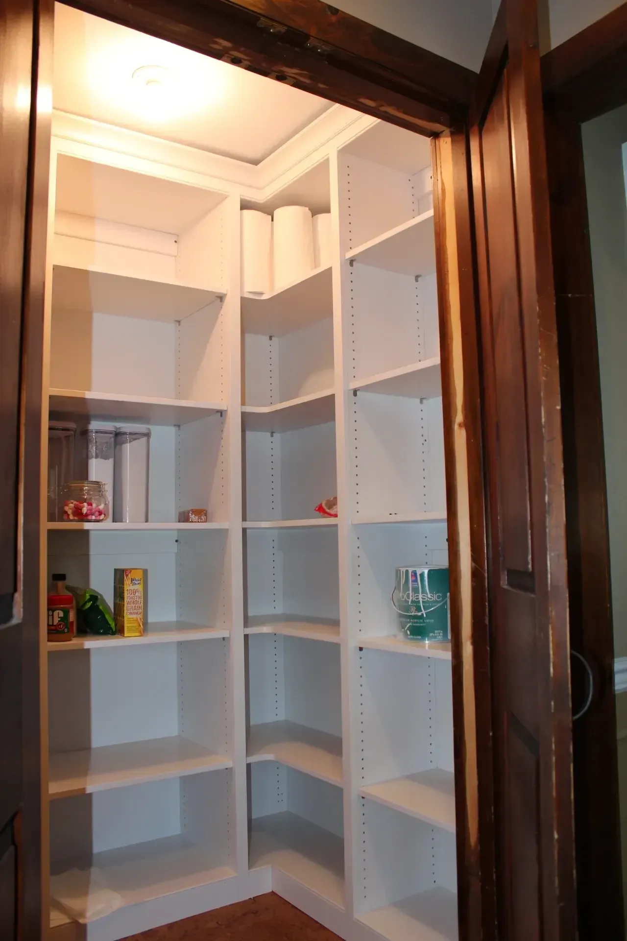 Corner pantry with white shelves and a brown doorframe.