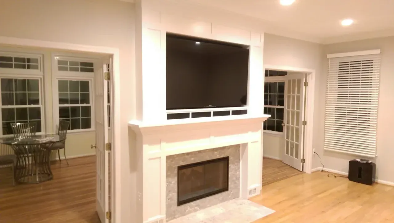Living room with fireplace, TV, and French doors leading to other rooms with windows.
