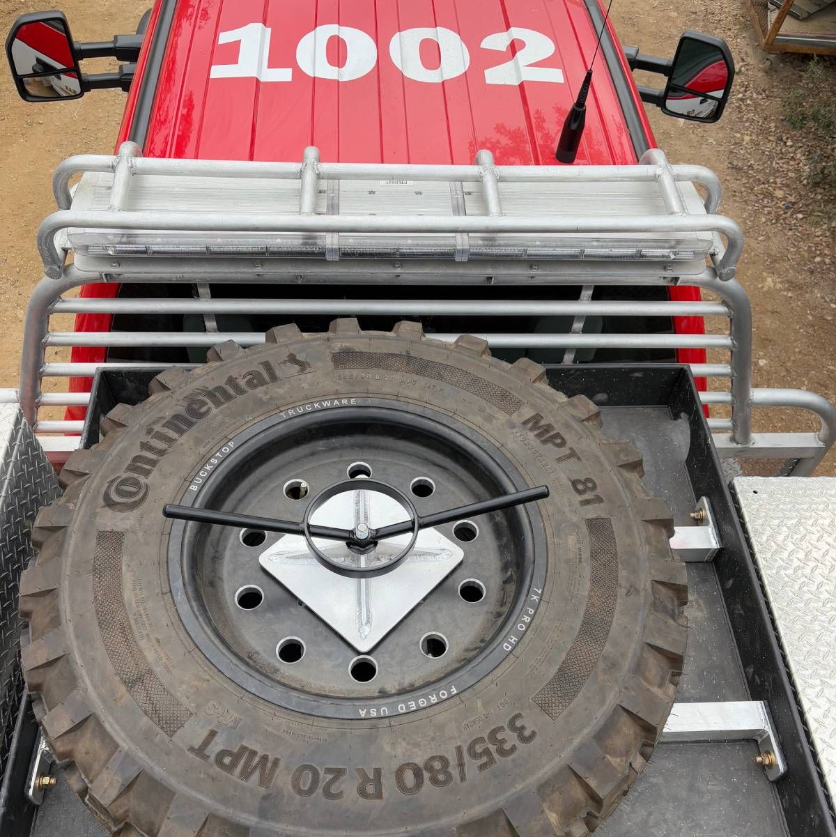 Red off-road buggy with white roll cage, rear spare tire, and number 1002 on hood viewed from above