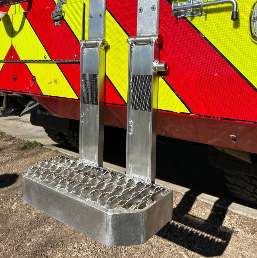 Rear of a red-and-yellow vehicle with reflective panels and a metal step platform