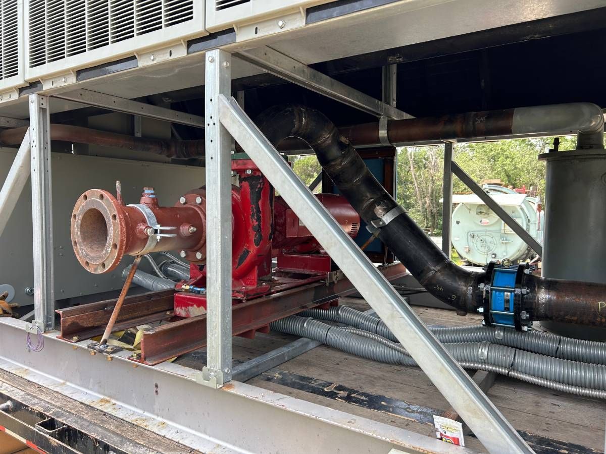 Industrial machinery with red piping and black hoses inside a metal equipment frame