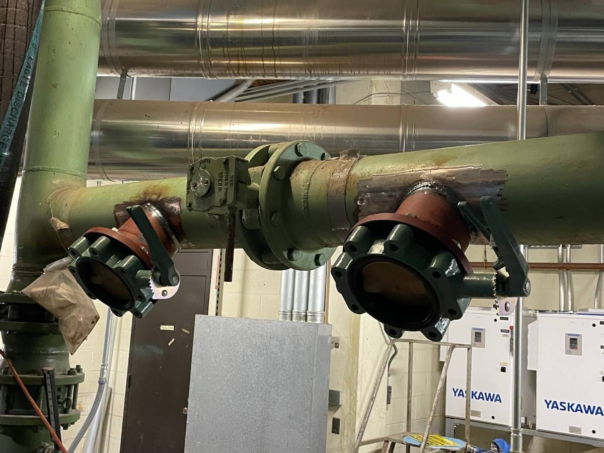 Industrial robotic arms mounted on a metal pipe in a factory setting