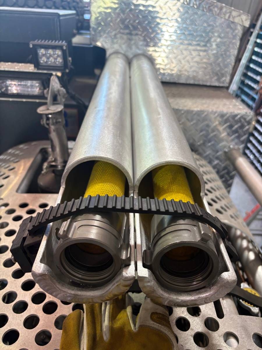 Close-up of twin silver pipes with black fittings and yellow insulation inside a metal industrial setup