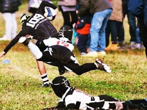 Un giocatore di rugby con il numero 18 sulla schiena viene placcato da un altro giocatore
