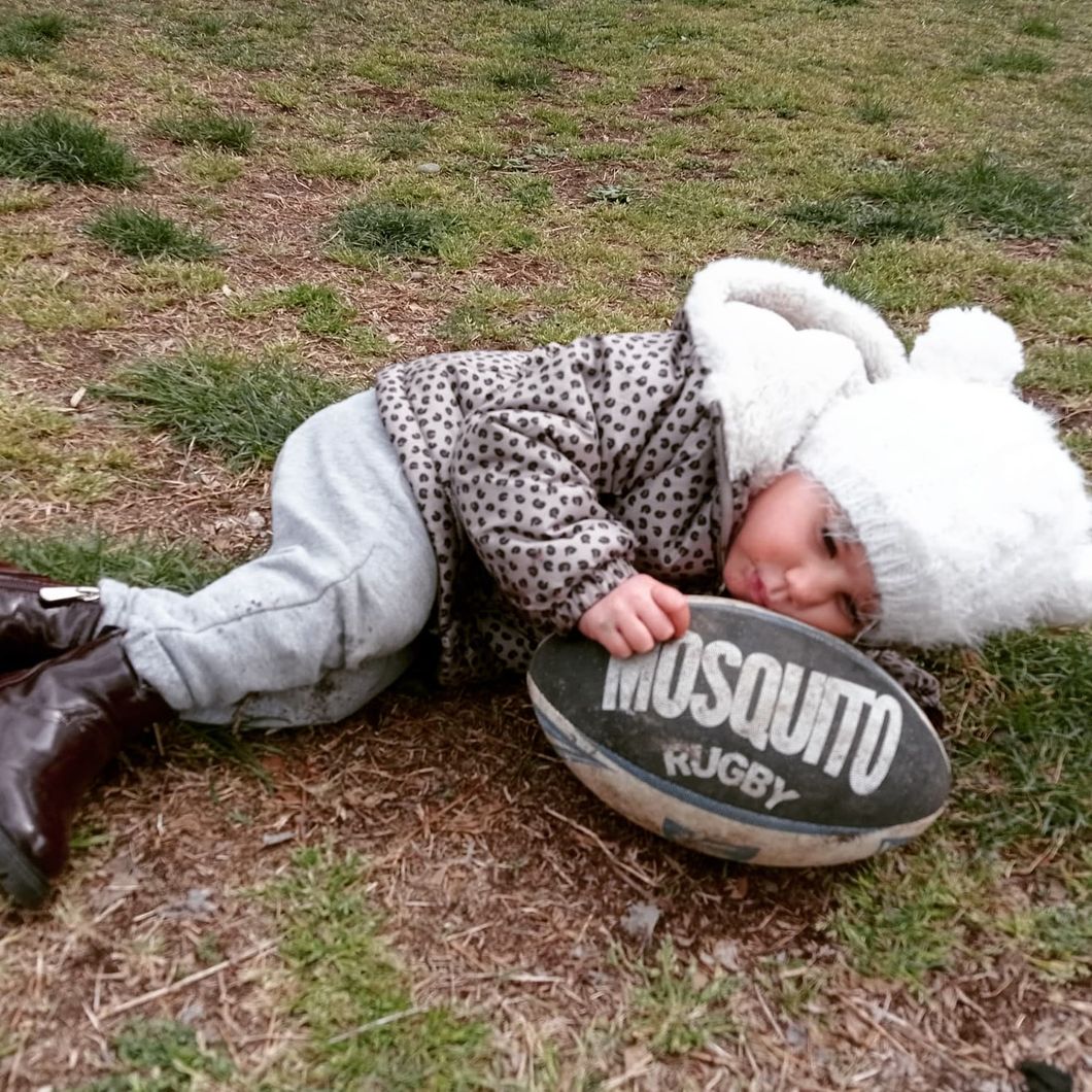 Un bambino è sdraiato a terra con una palla da rugby anti-zanzara