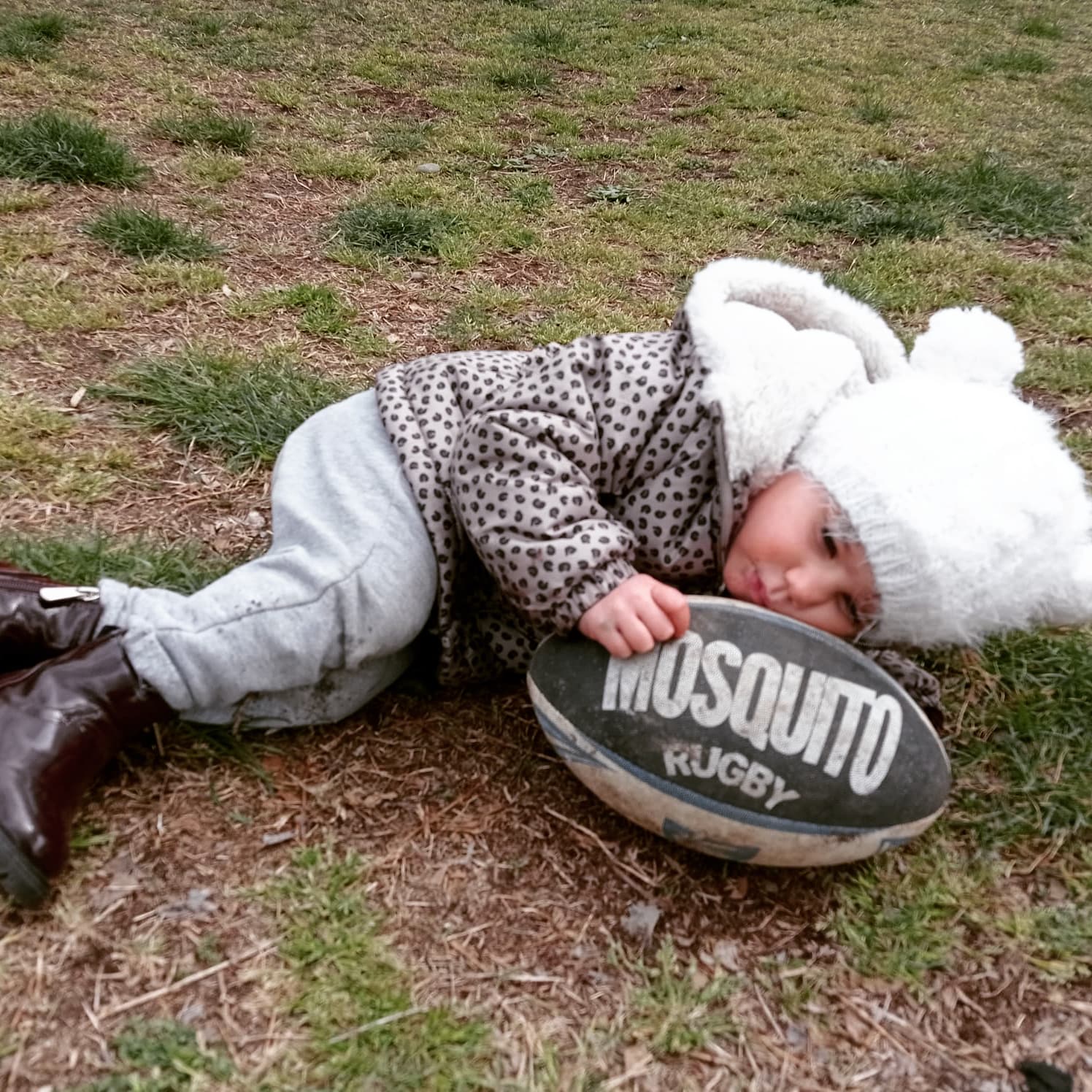 Un bambino è sdraiato a terra con una palla da rugby anti-zanzara