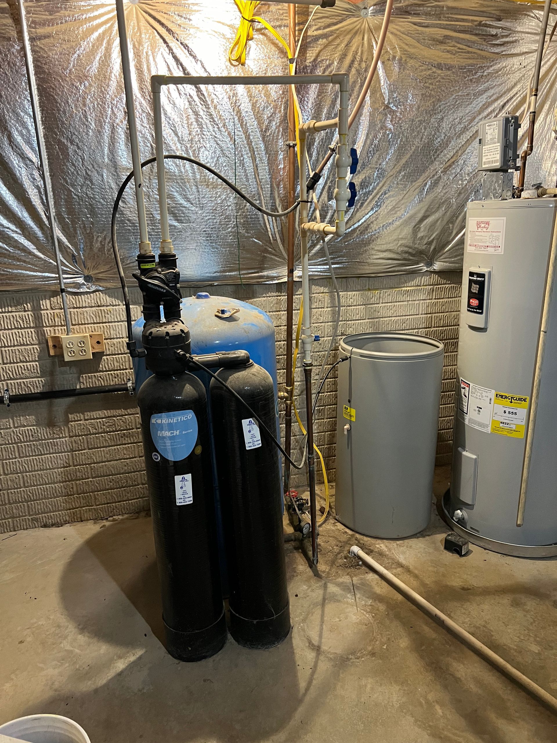 Insulated utility room with gas cylinders, pipes, and a water heater near a concrete floor.