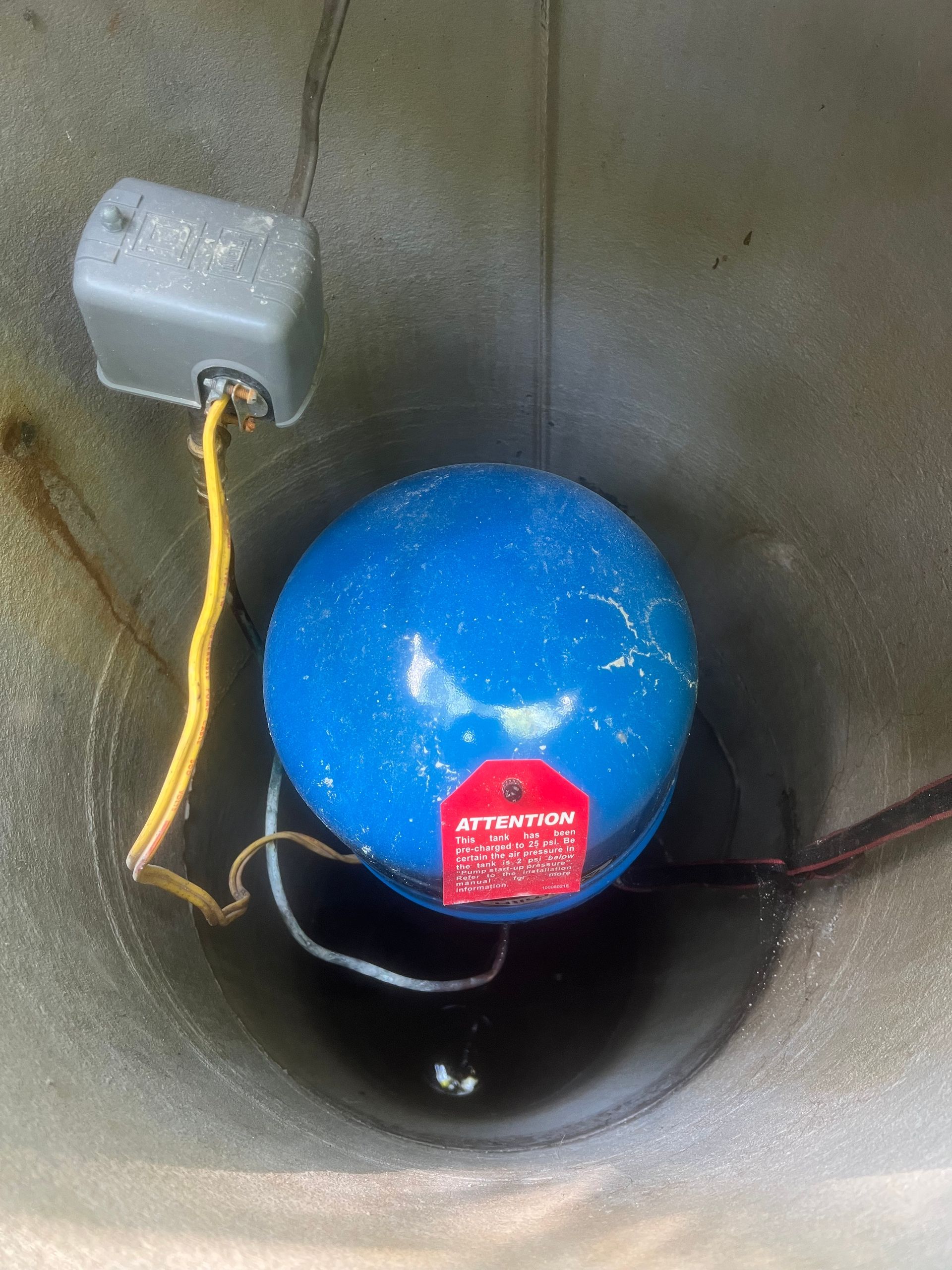 Blue float inside a circular tank with a gray sensor box and attached wires.