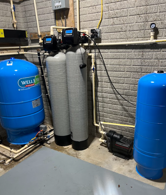 Water filtration system and well tanks in a basement, with pipes, pumps, and control panels.