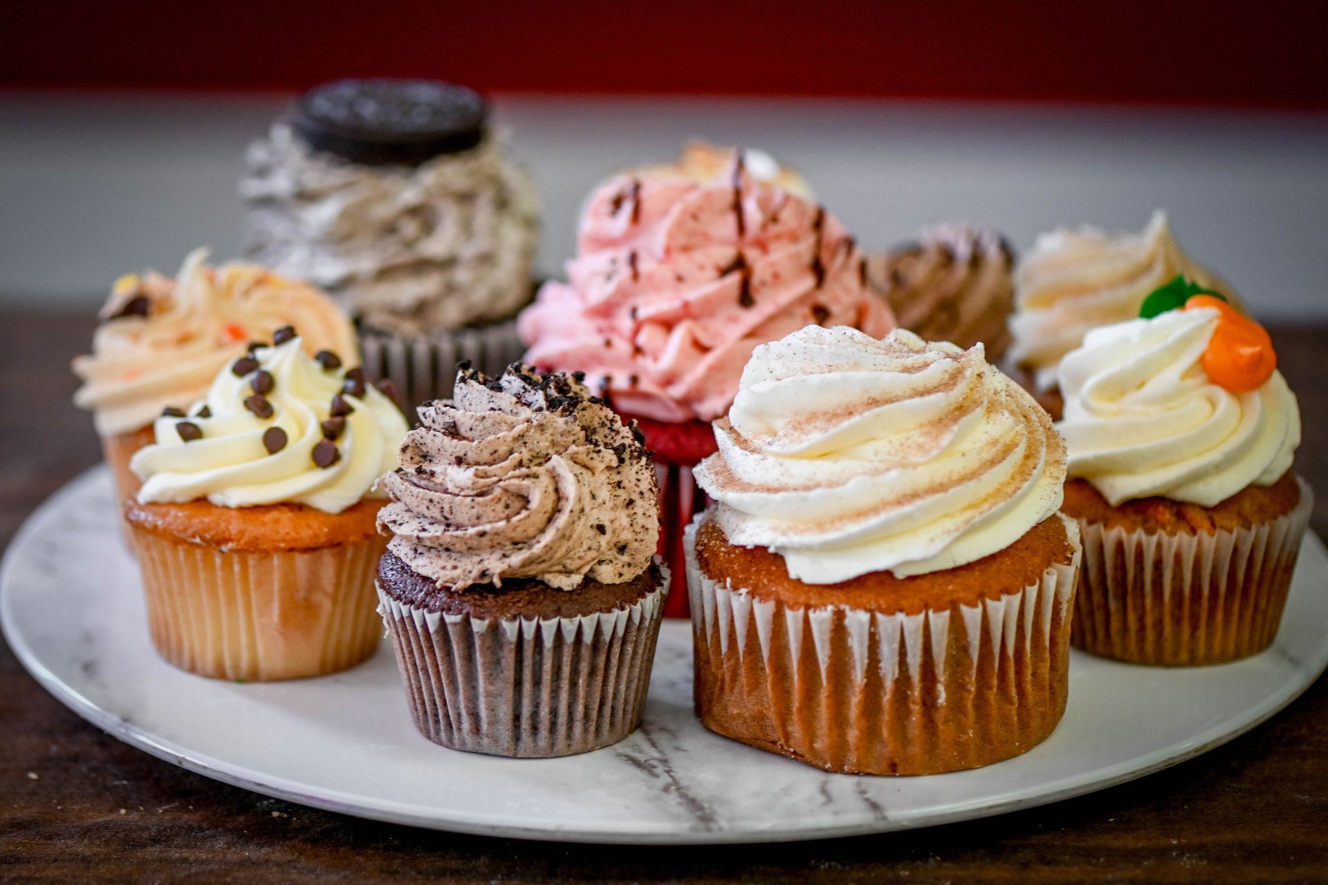 a plate of cupcakes with different flavors and frosting on a table .