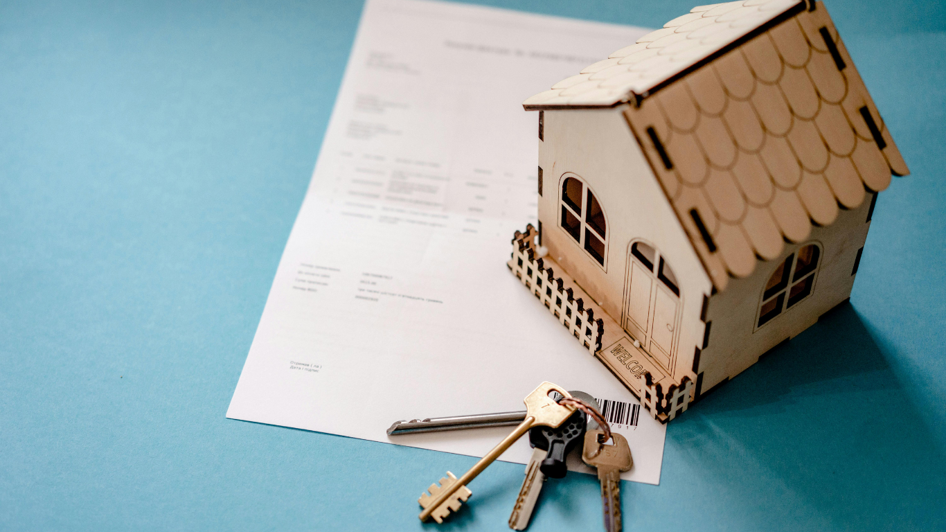 Toy house, keys, and document on a blue surface.