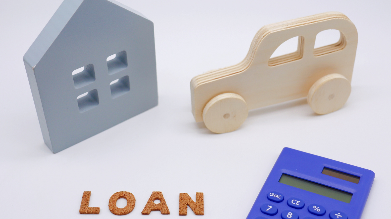 Wooden house and car models with a calculator and the word
