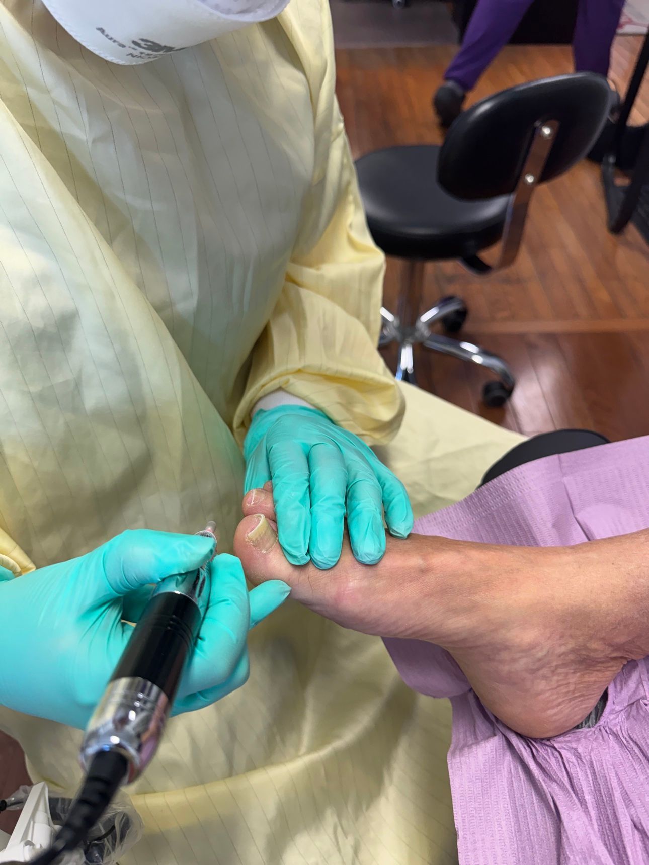 Foot care nurse using an electric file during a treatment