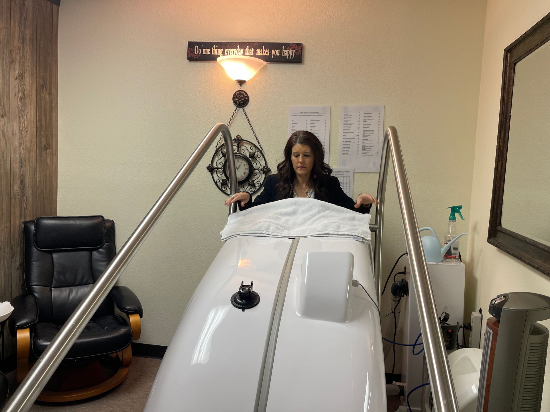 Woman seated in a white medical chamber with metal rails in a clinic room