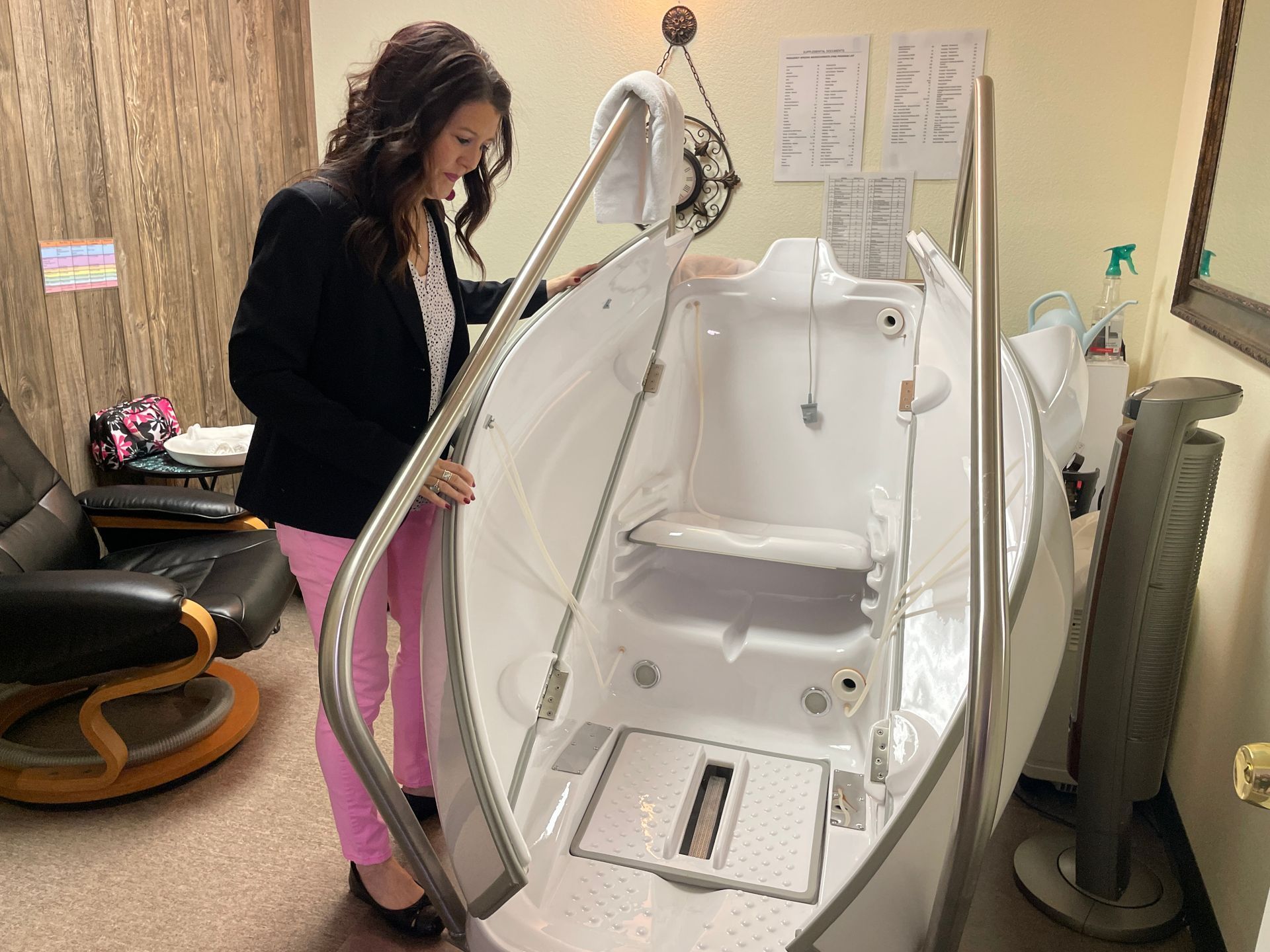 Woman standing beside a white therapeutic lift chair in a clinical room