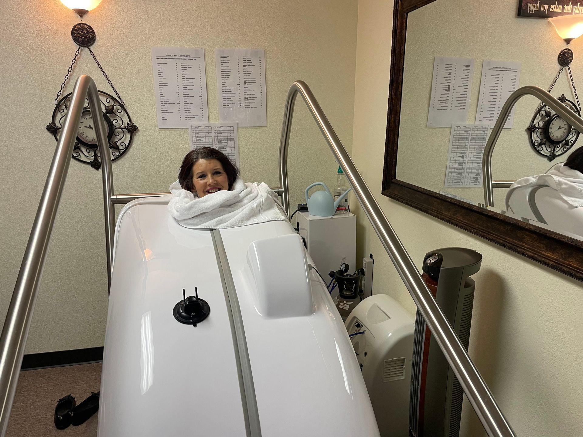 Person in a hydrotherapy tank at a spa, wrapped in a white towel in a clinical room.