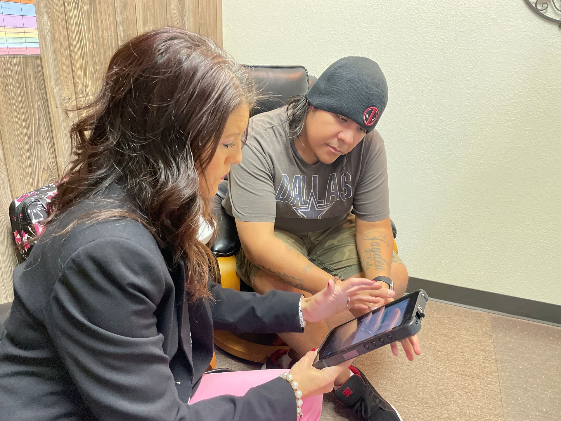 Two people sitting on the floor looking at a tablet together in a bright room.