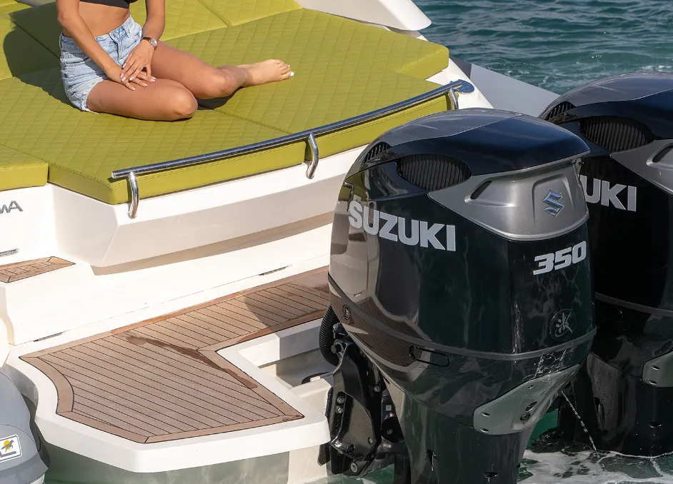 Persona su una barca, sdraiata vicino a un lettino prendisole con cuscini verdi. Due motori fuoribordo Suzuki 350.