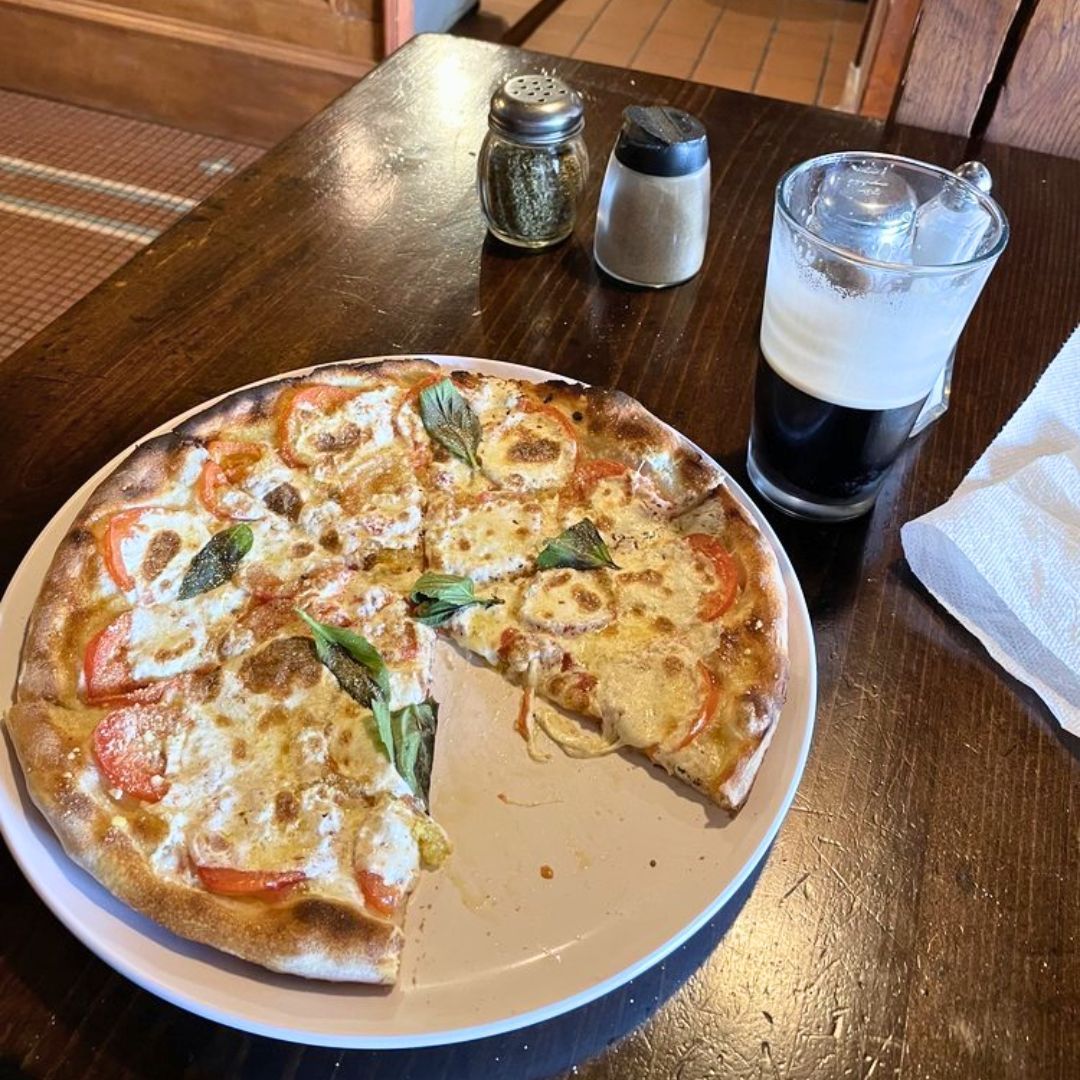A pizza with a slice taken out of it is on a plate on a table.