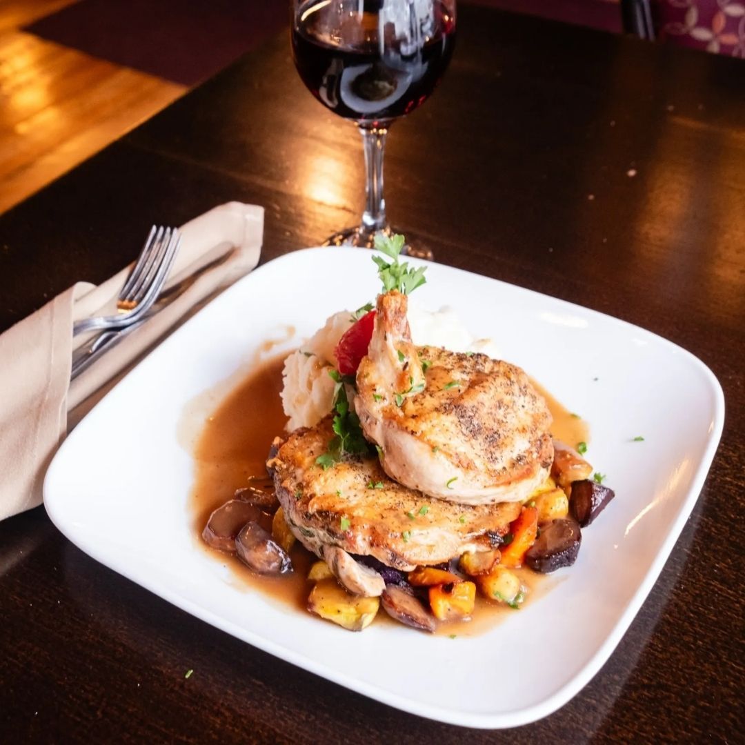 A plate of food on a table next to a glass of wine