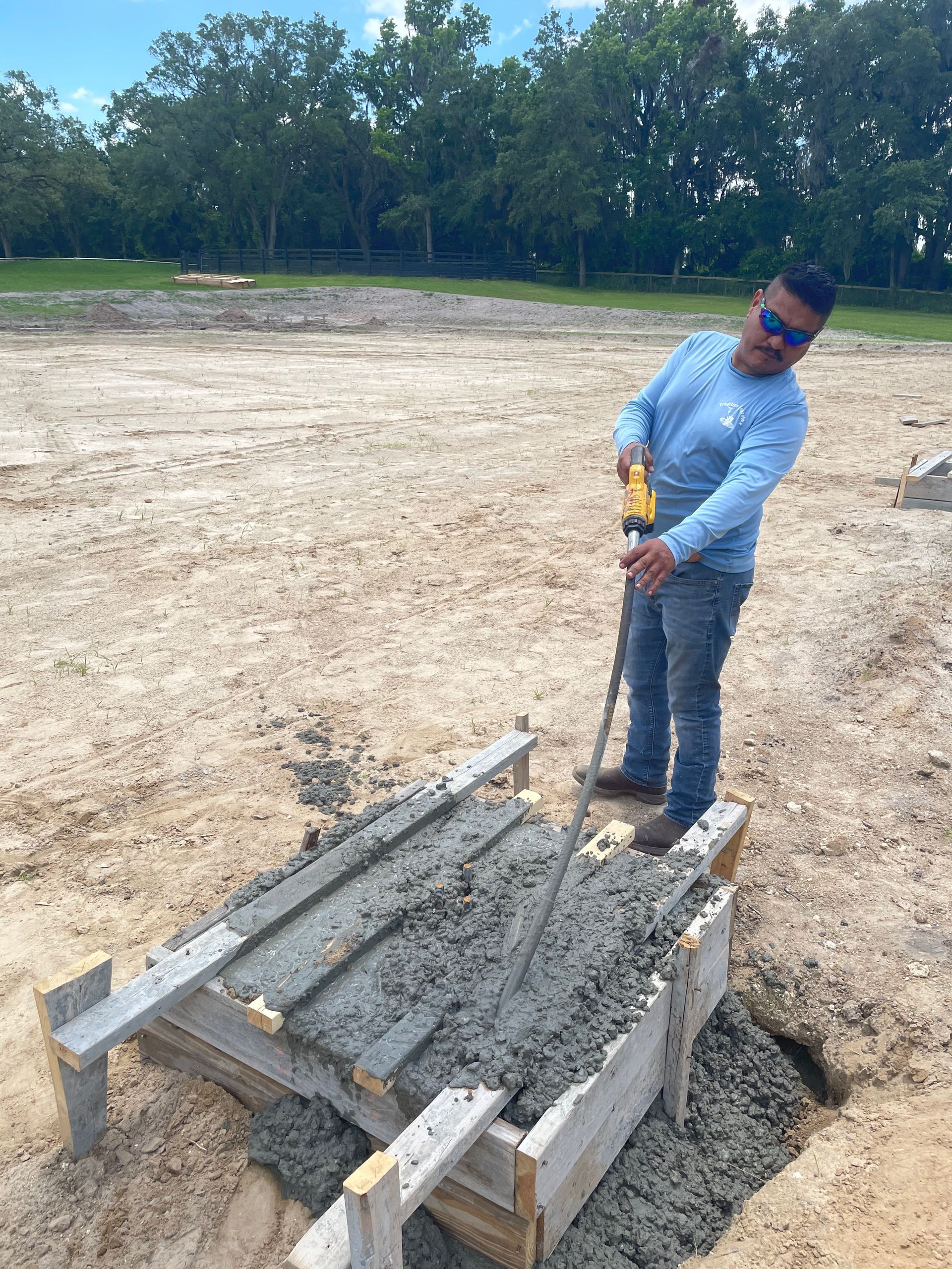 A man is standing next to a wooden pallet filled with concrete. Project done by C1 Foundations