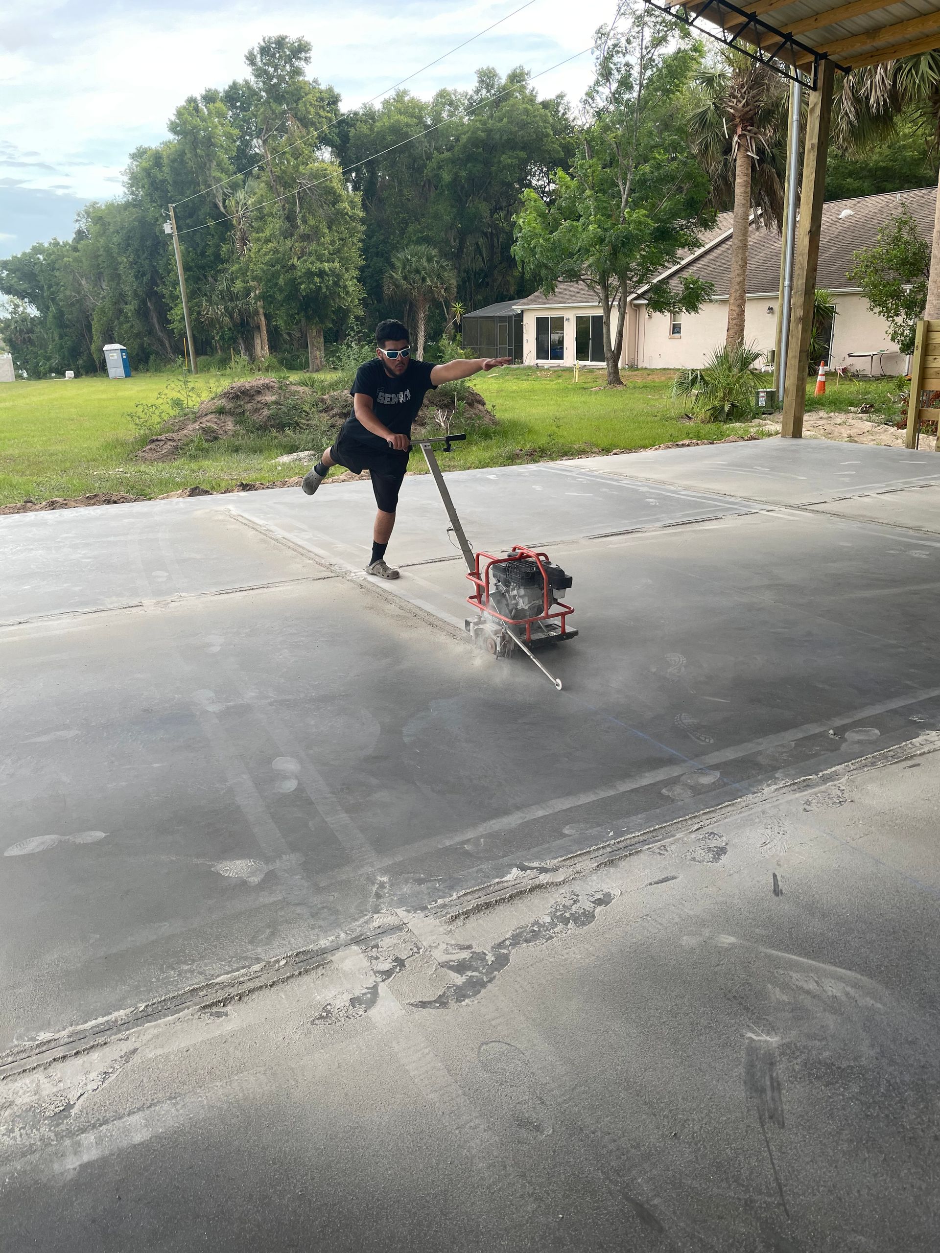 A man is using a machine to level a driveway. Project done by C1 Foundations