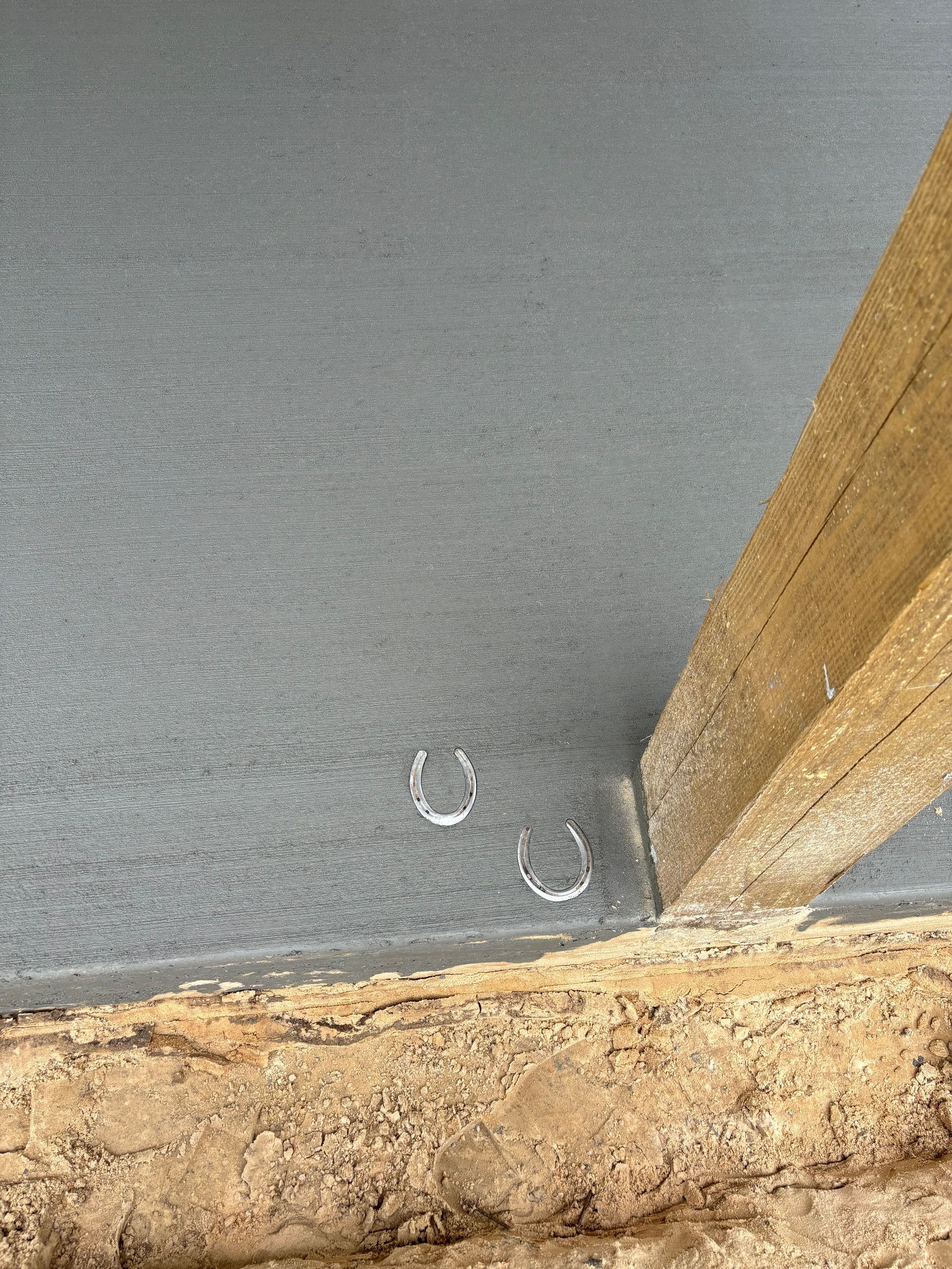 A close up of a wooden post and a horseshoe on the floor. Project done by C1 Foundations
