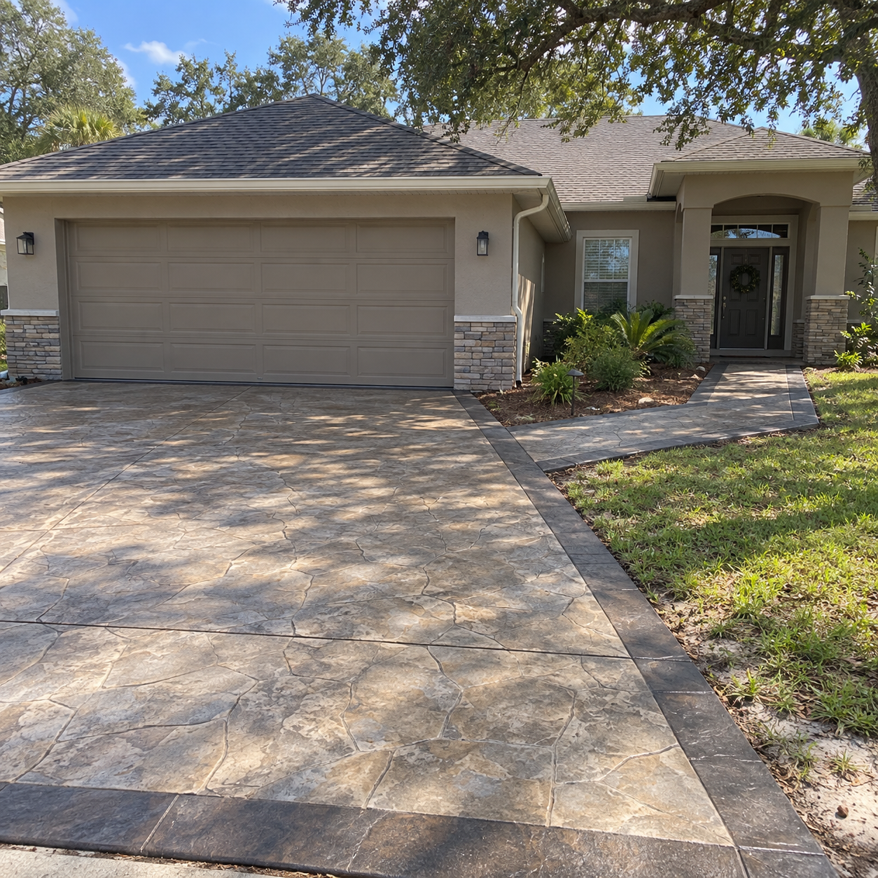 A finished stamped or stained concrete driveway with a matching walkway on an attractive Ocala-style home, shot in daylight 