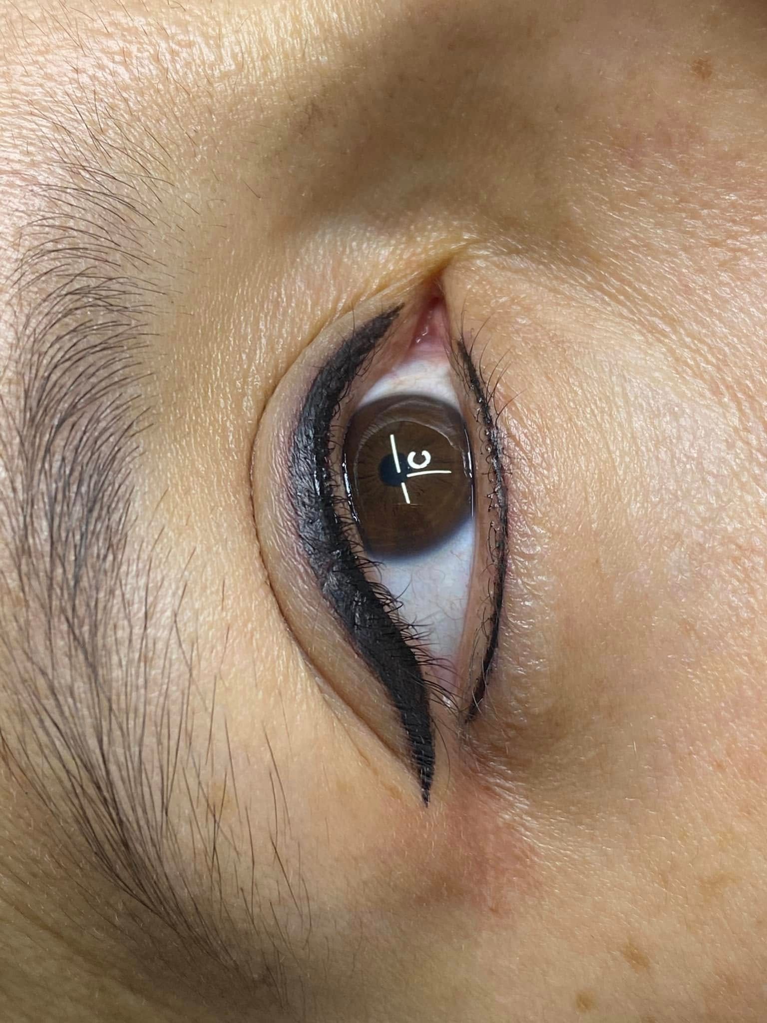 Close-up of an eye with dark eyeliner; brown iris, pale skin.