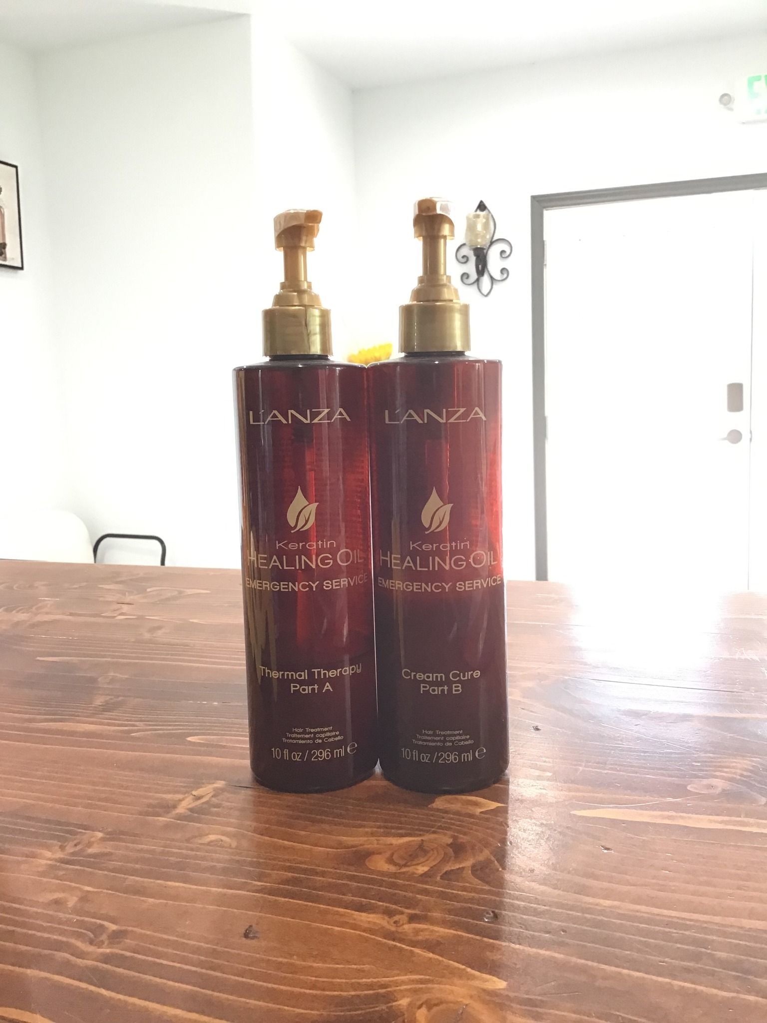 Two red bottles with gold pumps on a wooden table.