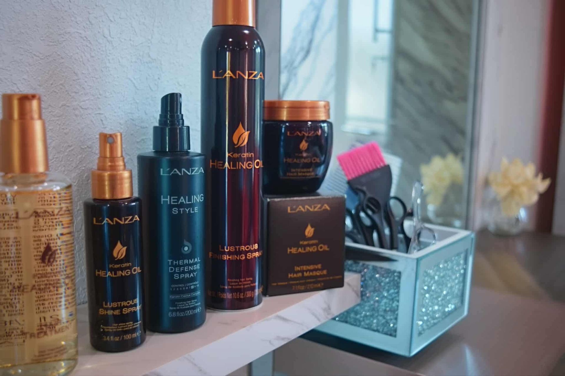 Hair care products with orange accents, and a container with styling tools.