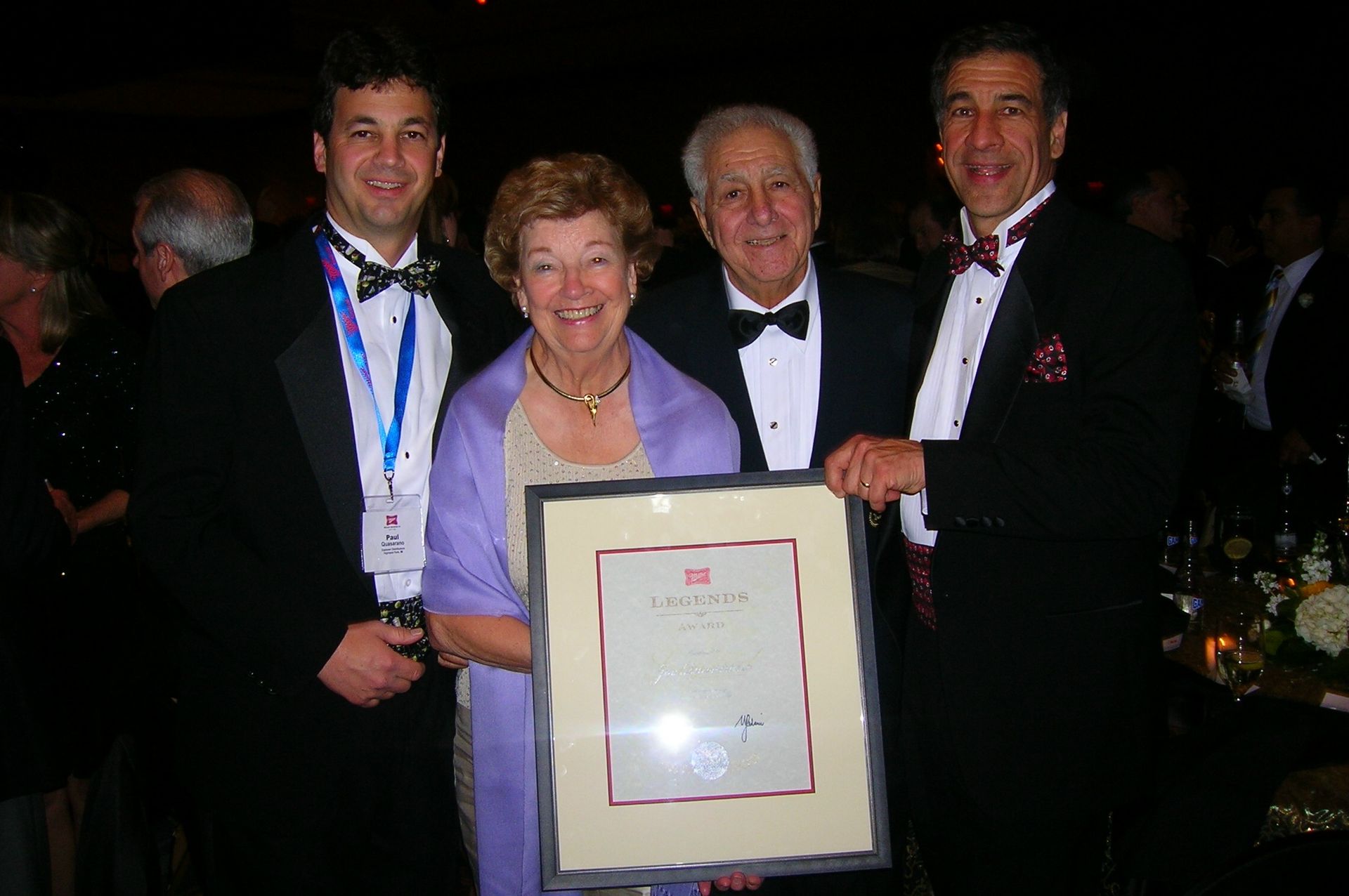 A group of people in tuxedos holding a framed certificate