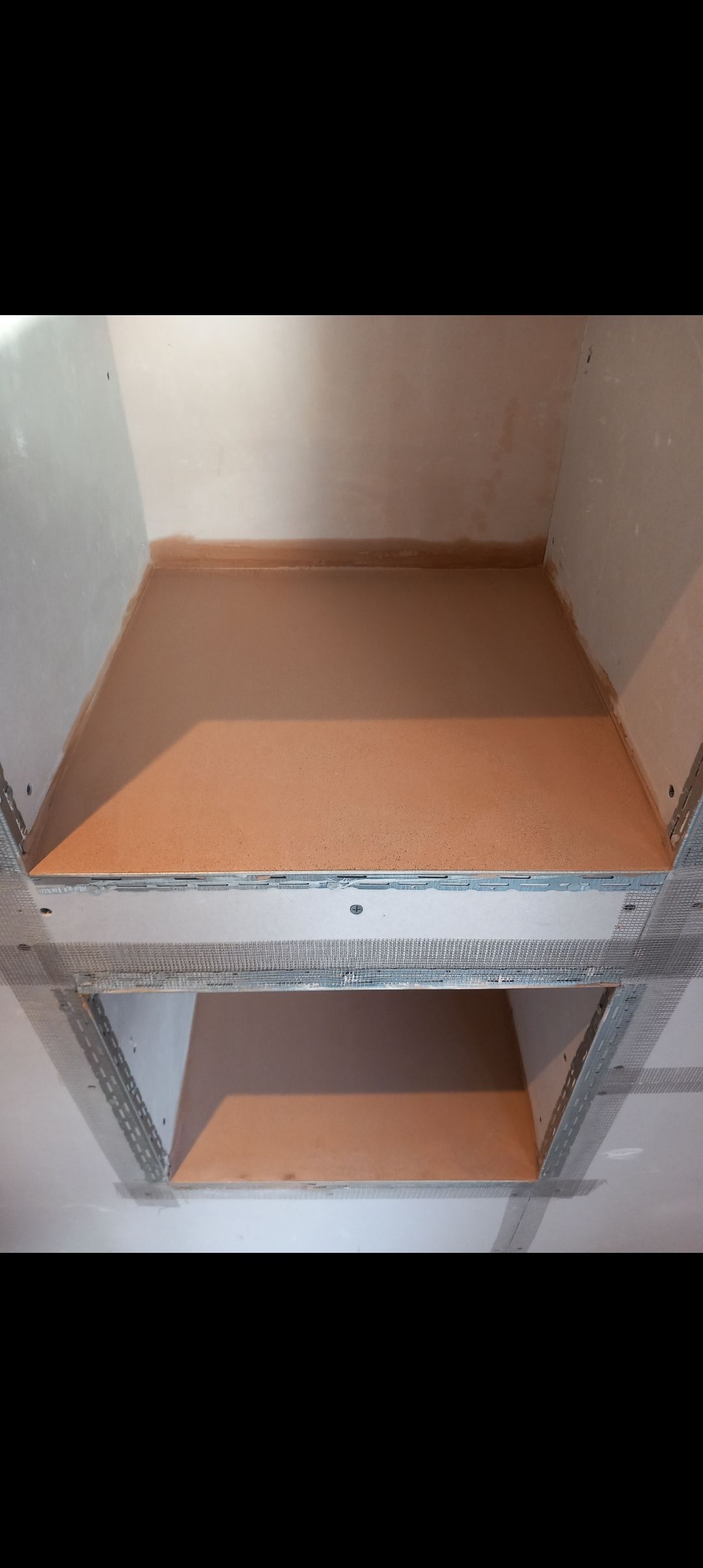 the inside of a media wall shelf after being plastered