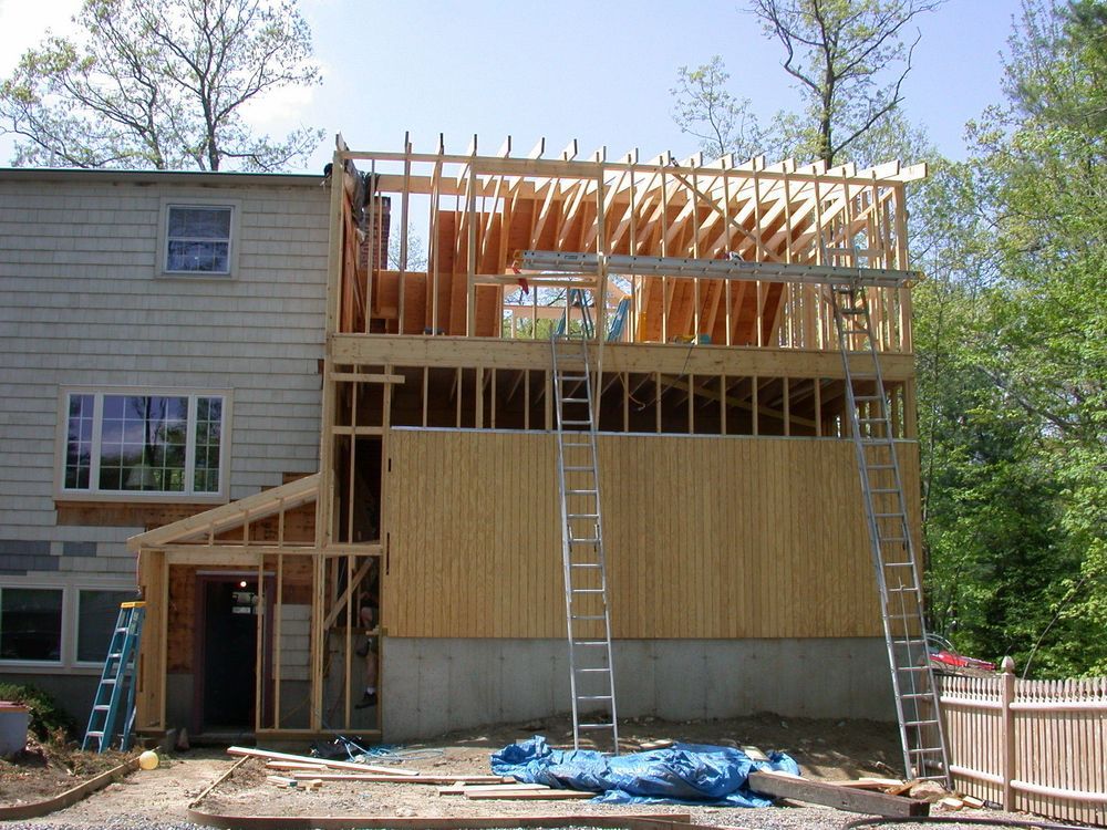 House under construction, framed with exposed wooden beams.