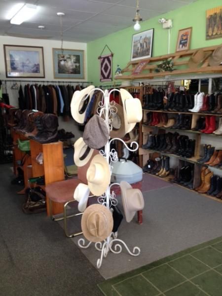Hat display in a boutique with shelves of shoes and clothing on green walls