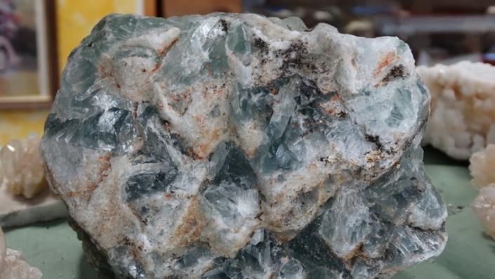 Rough gray-green mineral rock with white and tan patches on a surface