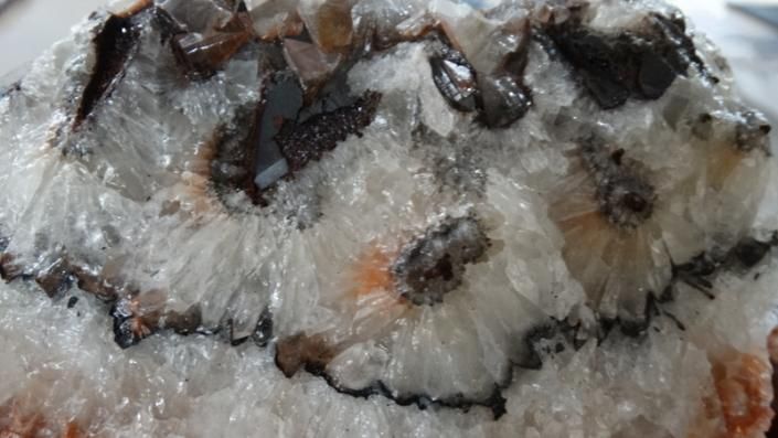 Close-up of a white and gray crystal rock with dark veins and hints of pink