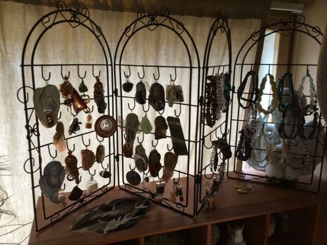 Decorative metal display racks with hanging jewelry and accessories on a wooden table