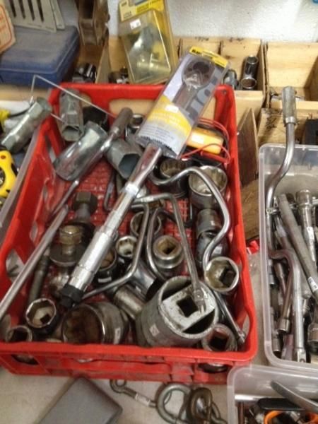 Red bin full of assorted metal sockets, ratchets, and hand tools on a workbench