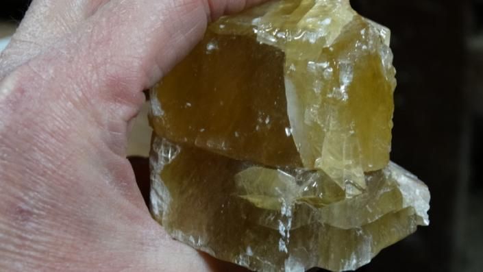 Hand holding a translucent yellow-brown crystal or mineral specimen