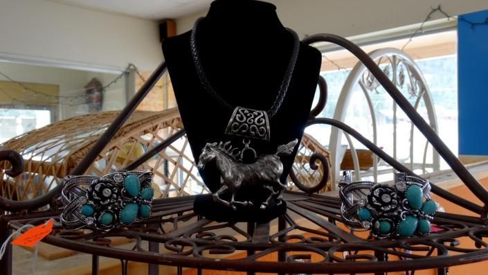 Black jewelry display with turquoise beaded bracelets and a necklace on a wire stand by a window