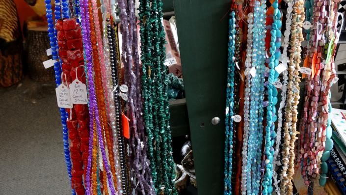 Colorful beaded necklaces hanging in a market stall, with strands in red, blue, turquoise, and white