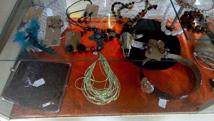 Assorted jewelry and accessories displayed in a glass case on an orange-lined surface